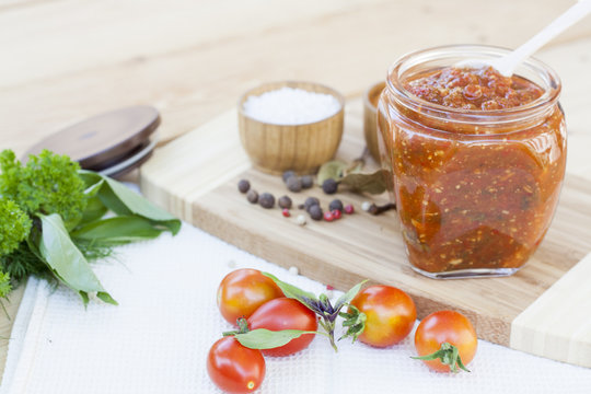 Homemade tomato sauce in glass jar with fresh tomatos, garlic, onion, herbs and spices