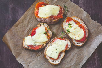 Bruschetta with tomato and mozzarella garnished with fresh thyme leaf and cracked pepper