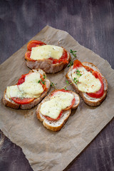 Bruschetta with tomato and mozzarella garnished with fresh thyme leaf and cracked pepper