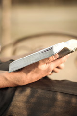 young man reading the Bible on a park bench