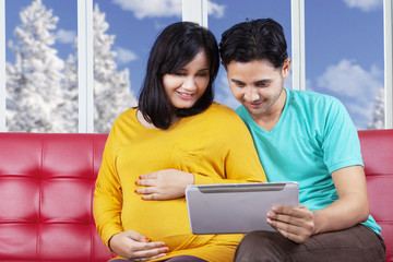 Fototapeta premium Man with pregnant wife using tablet
