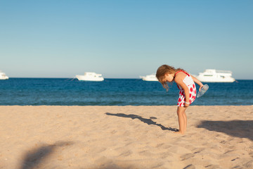Fototapeta premium little young girl searching in sea sand