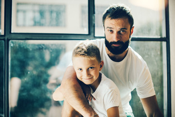 Portrait of a bearded man and his son near the window