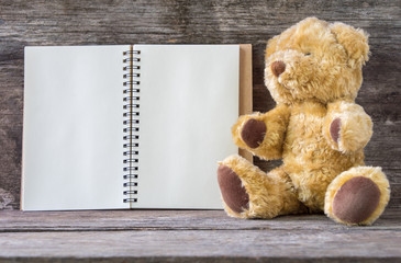 Open recipe book and Brown Bear on wooden background