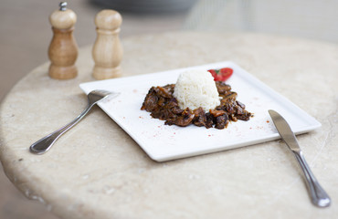 Бефстроганов с рисом. Кусочки мяса с рисом на тарелке.