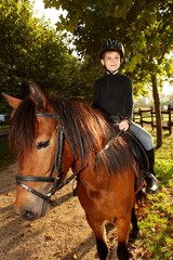 Little boy horseback riding in the green