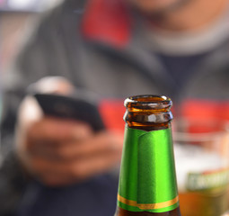 Man using smartphone. beer bottle