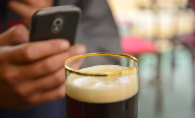Man using smartphone picturing glass of a beer