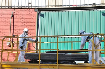 Trabajadores de amianto en máquina de elevación, con placas de fibrocemento