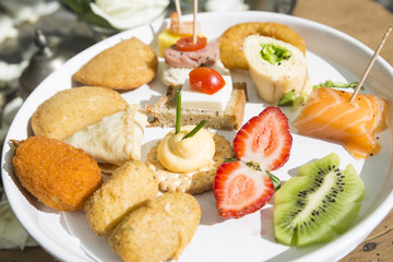 dish with fried snacks, fruit, salmon, bread and cheese