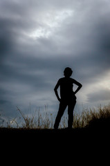 Silhouette of the woman standing lonely at the field during suns
