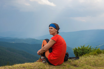 Naklejka na ściany i meble Woman hiker is sitting on the edge of the cliff and enjoy view