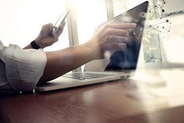 Obraz premium projektant pracy ręcznej i inteligentny telefon i laptop na drewnianym biurku