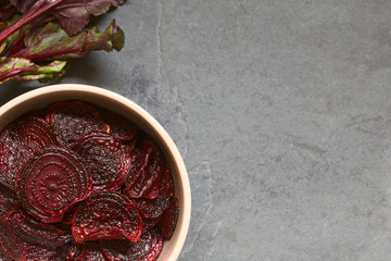 Fresh homemade beetroot chips in bowl, photographed overhead on slate with natural light (Selective Focus, Focus on the chips on the top)