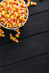 Halloween candy corns in bowl on black wooden background