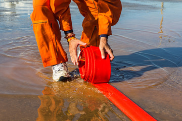 The Man rolling up a fire hose after filled  Water 