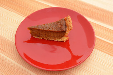 Red plate with a slice of pumpkin pie
