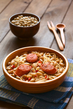 Traditional Chilean dish Porotos con Riendas, made of cooked beans, linguine, fried sausage, photographed with natural light (Selective Focus, Focus on the two sausage pieces in the front)