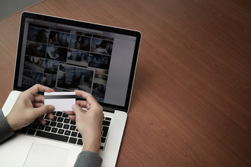 Fototapeta premium top view of hands using laptop and holding credit card with soci