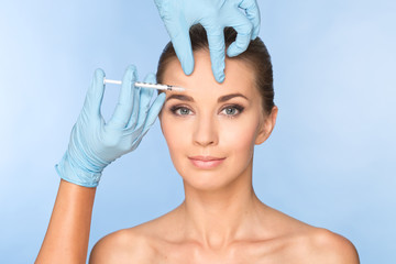 Attractive young woman receiving cosmetic injection with syringe