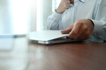 close up of business man hand working on laptop computer on wood