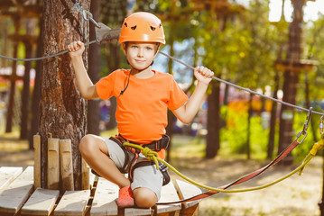 Happy boy having fun when playing at adventure park, holding