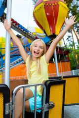 Cute little smiling girl riding a Carnival Carousel at summer