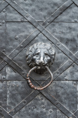 old iron door with lion's head doorknocker, reinforced with steel belts and rivets
