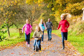 Mädchen rennen und fahren Roller bei Familien Spaziergang im Herbst Park vorweg