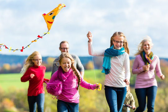Mädchen rennen und lassen Drachen steigen bei Familien Spaziergang im Herbst Park vorweg