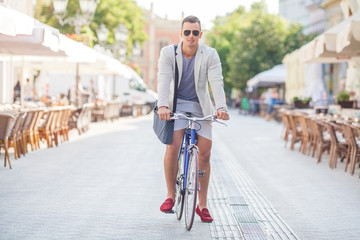 Handsome young businessman traveling to work by bicycle