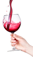Glass of red wine with splashes in hand isolated