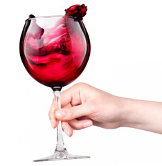 Glass of red wine with splashes in hand isolated
