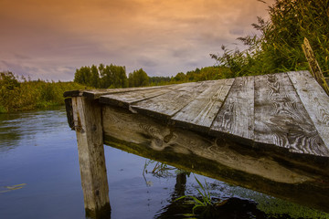 old wooden bridge over the river at sunset