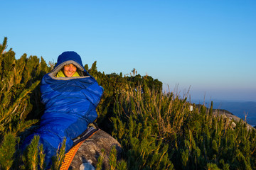 Young woman smiling inside blue sleeping bag