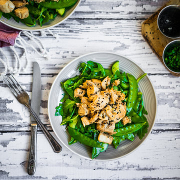 Grilled chicken with spinach,arugula and peas on rustic wooden b