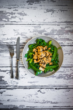 Grilled chicken with spinach,arugula and peas on rustic wooden b