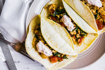 Tacos with chicken and vegetables on white wooden background