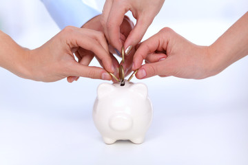 People putting coin into the piggy bank