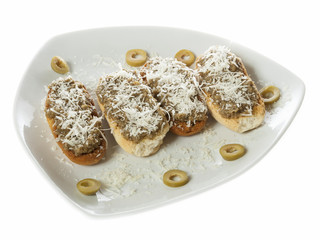 Four bruschetti with olives pate and grated cheese served on a white plate. Isolated on white.