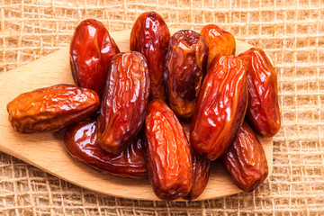 dried dates on wooden spoon cloth background