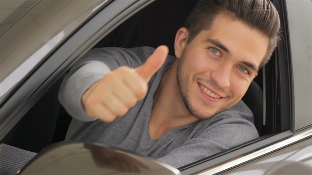 Young man doing thumps-up in car