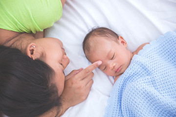 Baby sleeping with woman touching her forehead