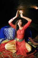 young pretty asian girl in bright colored interior on carpet