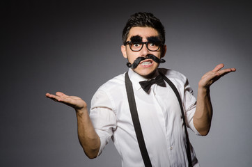 Young caucasian man with false moustache against gray