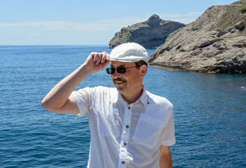 Mature man is posing on sea and cliffs background, Crimea.