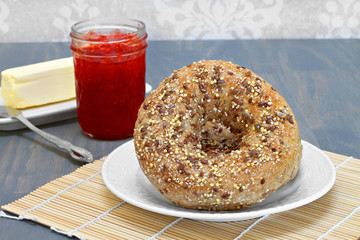 Whole grain, multi seeded bagels with a side of butter and jam.