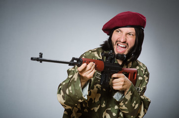 Fototapeta premium Soldier with handgun against gray