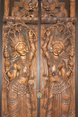 A vintage brass keyhole and religious ornament on an old exotic brown ornate Hindu temple door.