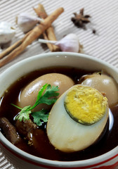stewed eggs or eggs and pork in brown sauce by Thai food .